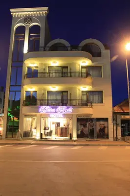 a large white building with purple neon signs on it at Guest House Palazzo in Byala