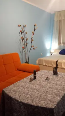 a living room with an orange couch and a bed at Аria B&B in Burgas City