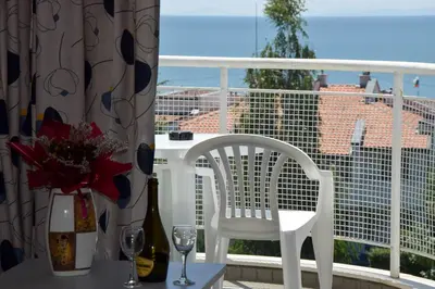 a balcony with a white chair and a table and a window at Sineva Park Hotel - All Inclusive in Sveti Vlas