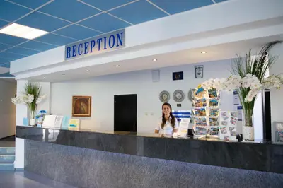 a woman standing at a reception counter in a lobby at Sineva Park Hotel - All Inclusive in Sveti Vlas