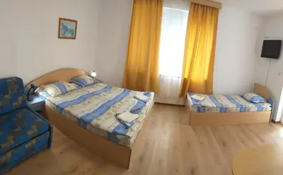 a bedroom with two beds and a chair at Primorsko Apartments in Primorsko