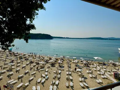 a beach with chairs and umbrellas and people on it at Family Hotel Teos in Kiten