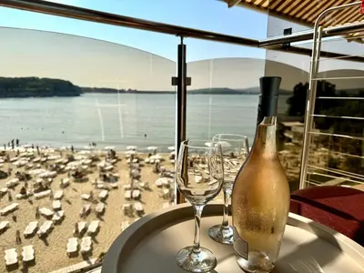 a table with a bottle and two glasses on a beach at Family Hotel Teos in Kiten