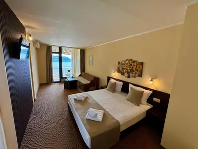 a hotel room with a bed and a living room at Family Hotel Teos in Kiten