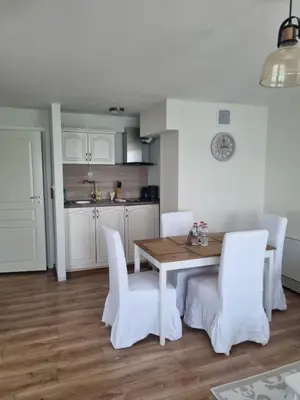 a kitchen with a wooden table and white chairs at Villa Elea in Nesebar