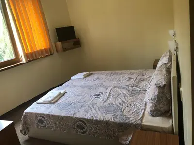 a bedroom with a bed with a blanket and a window at Sunny Paradise Family Hotel in Kiten
