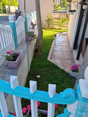 a white picket fence with flowers in a yard at Villa Izgrev 24а in Chernomorets