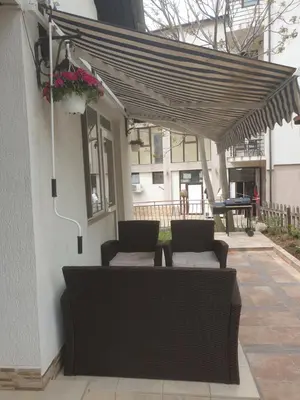 a patio with two chairs and awning on a house at Villa Izgrev 24а in Chernomorets