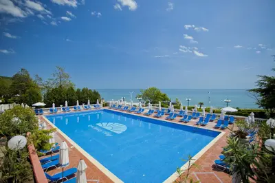 a large swimming pool with lounge chairs and the ocean at Villas Elenite in Elenite