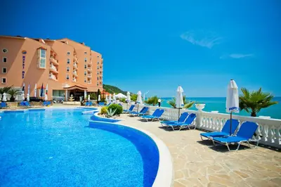 a resort with a swimming pool and chairs and the ocean at Royal Bay Hotel - All Inclusive in Elenite