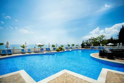 a large pool with chairs and the ocean in the background at Royal Bay Hotel - All Inclusive in Elenite