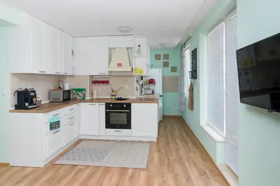 a kitchen with white cabinets and a tv on the wall at Soulful Apartments - Horizon in Varna City
