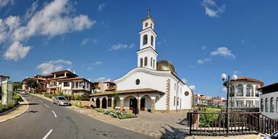 a white church with a steeple on the side of a street at Arena 65m2 - 1 bedroom, 1st line to the beach in Sveti Vlas