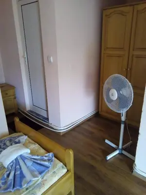 a bedroom with a bed and a fan next to a door at Morski Rai Rooms in Byala