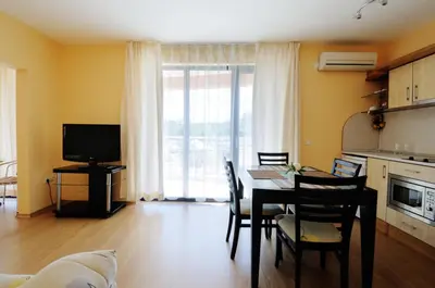 a living room with a table and chairs and a television at Guest House Daris in Sozopol