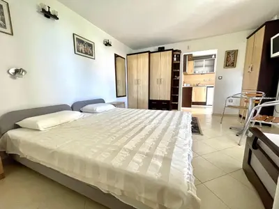 a bedroom with a large bed and a kitchen at Guest House Daris in Sozopol