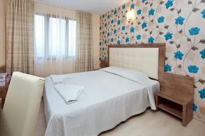 a bedroom with a white bed with blue flowers on the wall at Relax Holiday Complex & Spa in Sunny Beach