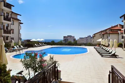 a swimming pool with chairs and umbrellas next to some buildings at Relax Holiday Complex & Spa in Sunny Beach