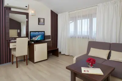 a living room with a couch and a table with a television at Relax Holiday Complex & Spa in Sunny Beach