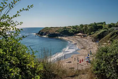 a beach with umbrellas and people on the beach at Aparthotel Romance in Kiten