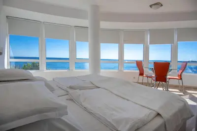 a bedroom with a large bed and chairs in front of windows at Aparthotel Romance in Kiten