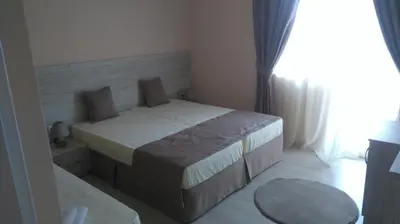 a bedroom with two beds and a large window at Guest House Adriya in Primorsko