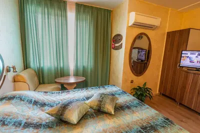a hotel room with a bed and a television at Hotel Color in Varna City