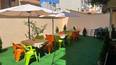 a patio with tables and chairs with an umbrella at Hotel Color in Varna City