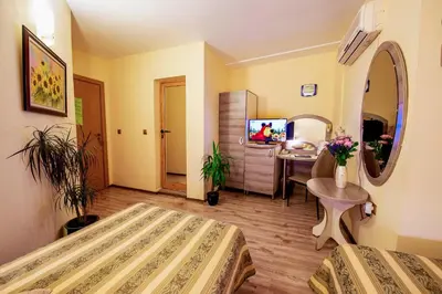 a bedroom with a bed and a table and a desk at Hotel Color in Varna City