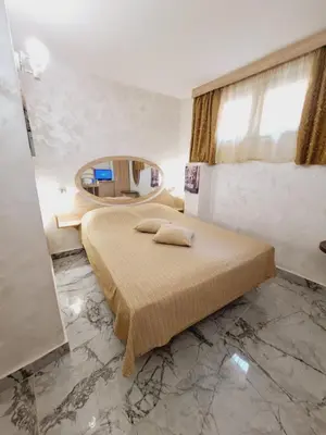 a bedroom with a bed and a round mirror at Hotel Color in Varna City