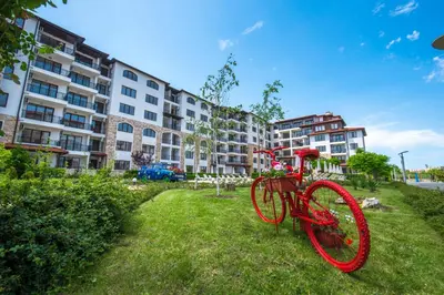 a red bike parked in the grass in front of a building at Apollon Apartments in Nesebar