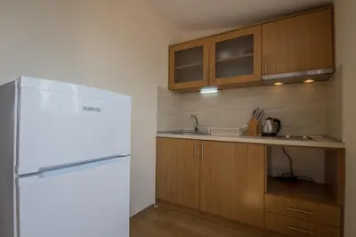 a kitchen with a white refrigerator and wooden cabinets at Семеен хотел Бриз in Sozopol