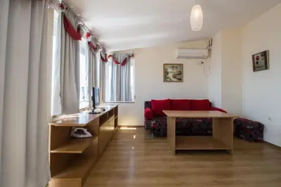 a living room with a desk and a red couch at Семеен хотел Бриз in Sozopol