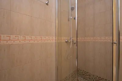 a shower with a glass door in a bathroom at Семеен хотел Бриз in Sozopol