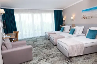 a hotel room with two beds and a table and chairs at Hotel Wela - Premium All Inclusive in Sunny Beach