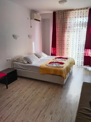a bedroom with a large bed with red curtains at Apartament Janet in Pomorie