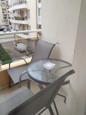 a glass table and two chairs on a balcony at Apartament Janet in Pomorie