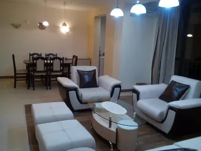 a living room with white furniture and a dining room at Byala Relax Apartments in Byala