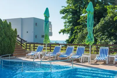 a group of chairs and umbrellas next to a swimming pool at Семеен хотел Golden Place in Sozopol
