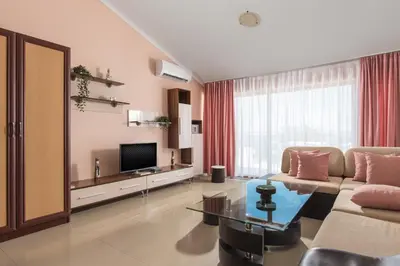 a living room with a couch and a television at Семеен хотел Golden Place in Sozopol