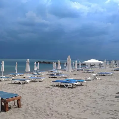 a beach with chairs and umbrellas on the sand at Belchevi Apartments in Burgas City