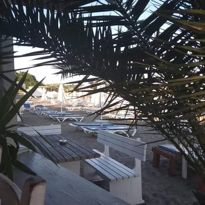 a view of a beach with a bench and boats at Belchevi Apartments in Burgas City