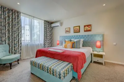 a bedroom with a bed and a chair and a window at City Boutique Inn in Varna City