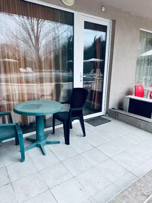 a patio with a table and chairs and a window at Stella Udacha Apartments & Studios in Sunny Beach