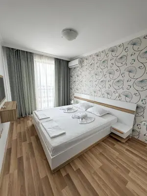 a bedroom with a large white bed and a wall at OLYMP Apart-Complex in Sveti Vlas