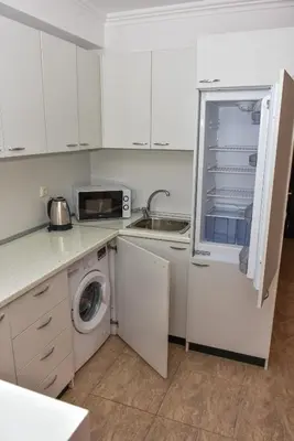 a kitchen with white cabinets and a washer and dryer at OLYMP Apart-Complex in Sveti Vlas
