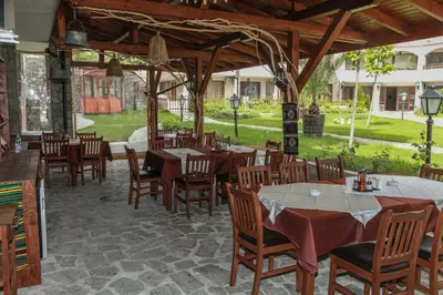 a restaurant with wooden tables and chairs and a patio at OLYMP Apart-Complex in Sveti Vlas