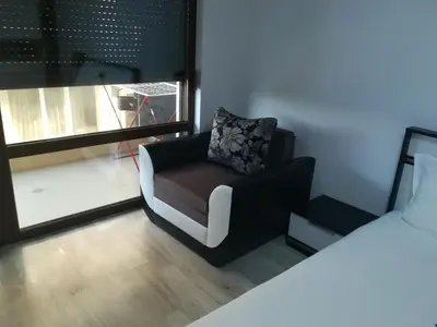 a living room with a chair and a bed at Апартамент Дарко in Pomorie