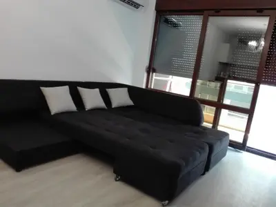 a black couch in a living room with windows at Апартамент Дарко in Pomorie
