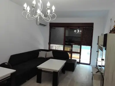 a living room with a black couch and a chandelier at Апартамент Дарко in Pomorie